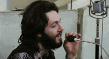 a man singing into a microphone with a beard