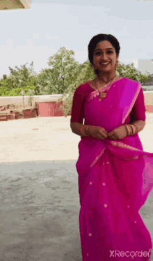 a woman is wearing a pink saree and smiling while standing outside