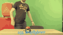 a man wearing a 365 voyager shirt stands in front of a green background