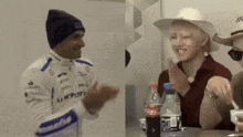 a bottle of coca cola sits on a table next to a man wearing a hat
