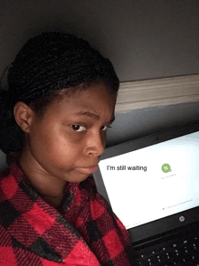 a girl sitting in front of a laptop with the words i 'm still waiting on the screen