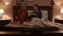 a man and a woman are sitting on a bed with a hd logo in the corner