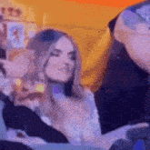 a woman is sitting next to a man at a party and looking at something .