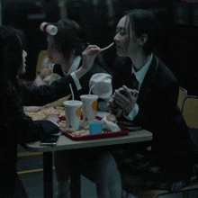 a woman with curlers in her hair sits at a table with a tray of french fries and drinks