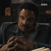 a man in a suit and tie is sitting at a table with a book in his hand .