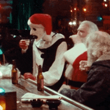 a man in a santa hat sits at a bar holding a drink