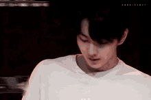 a young man in a white t-shirt is looking down at something