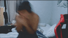 a blurry photo of a person laying on a bed with a red chair in the background