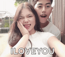 a man and a woman are posing for a picture and the woman is sticking her tongue out and the man is saying i love you
