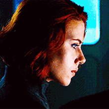 a close up of a woman 's face with red hair and a blue background .