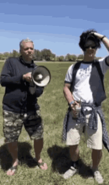 a man holding a megaphone next to another man in a field