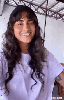 a woman with long hair and a nose ring is smiling and wearing a white shirt .