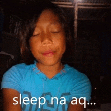 a young girl with her eyes closed is wearing a blue shirt that says sleep na aq .