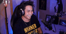 a man wearing headphones and a winner shirt smiles
