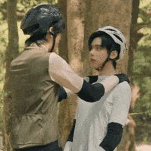 a man wearing a helmet helps another man with his helmet