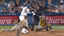 a dodgers player swings at a pitch in front of an advertisement for uru