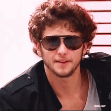 a close up of a man wearing sunglasses and a jacket