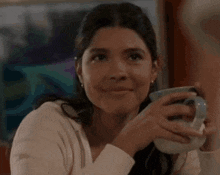 a woman is holding a cup of coffee and making a face .