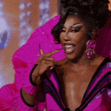 a woman wearing a pink and purple dress and earrings is eating something