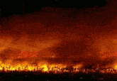 a plane is flying over a burning field at night