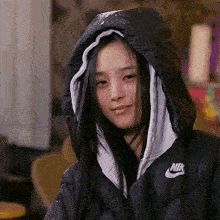 a woman wearing a nike jacket with a hood on her head