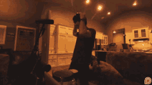a man is playing drums in a living room with a p logo in the corner
