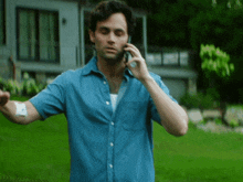 a man in a blue shirt is talking on his cell phone