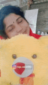 a woman is holding a yellow teddy bear in front of her face
