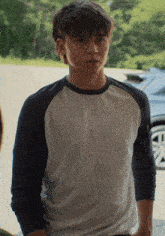 a young man wearing a white shirt with blue sleeves