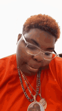 a man wearing glasses and a necklace has a picture of a man on it
