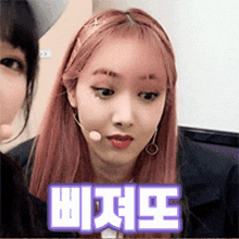 a woman with pink hair has a microphone on her head and the word wizk is on the bottom of her face