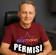 a man wearing a red starmaker t-shirt holds a sign that says permisi