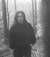 a woman in a black sweater is walking through a foggy forest