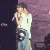 a man and a woman are standing next to each other on a stage . the woman is holding a microphone .