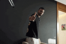 a man giving a thumbs up in a room