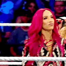 a woman with pink hair is in a wrestling ring