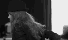 a black and white photo of a woman wearing a hat and jacket .
