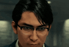 a man wearing glasses is looking at the camera with a serious look on his face