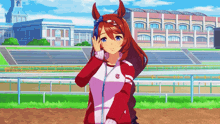 a girl with a horse on her head is standing in front of a race track .