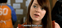 a woman is saying " i wanna blow you " in front of a man in an orange shirt .
