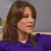 a woman in a purple shirt is making a funny face while sitting on a couch .