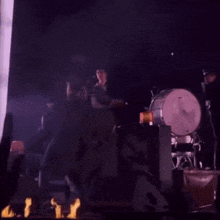 a group of people standing in front of a stage with flames in the background