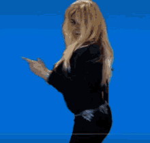 a woman with blonde hair is wearing a black sweater and black pants