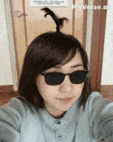 a woman wearing sunglasses takes a selfie in front of a door that has pixverse.ai written on it