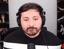 a man with a beard is wearing headphones and a black shirt
