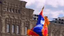 a red white and blue flag is waving in front of a large building
