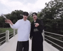 two men are standing on a bridge in a park .