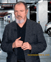 a man in a suit is standing in a parking garage with a reviewonivere.com logo in the bottom right corner