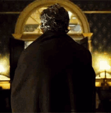 a man in a black coat is standing in a dark room