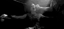 a woman is sitting in a boxing ring with her arms outstretched and water coming out of her mouth .